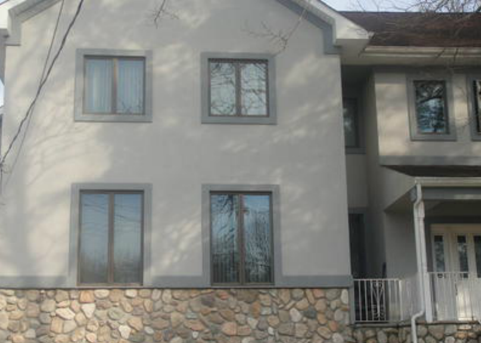 tan stucco house front with stone bottom lining